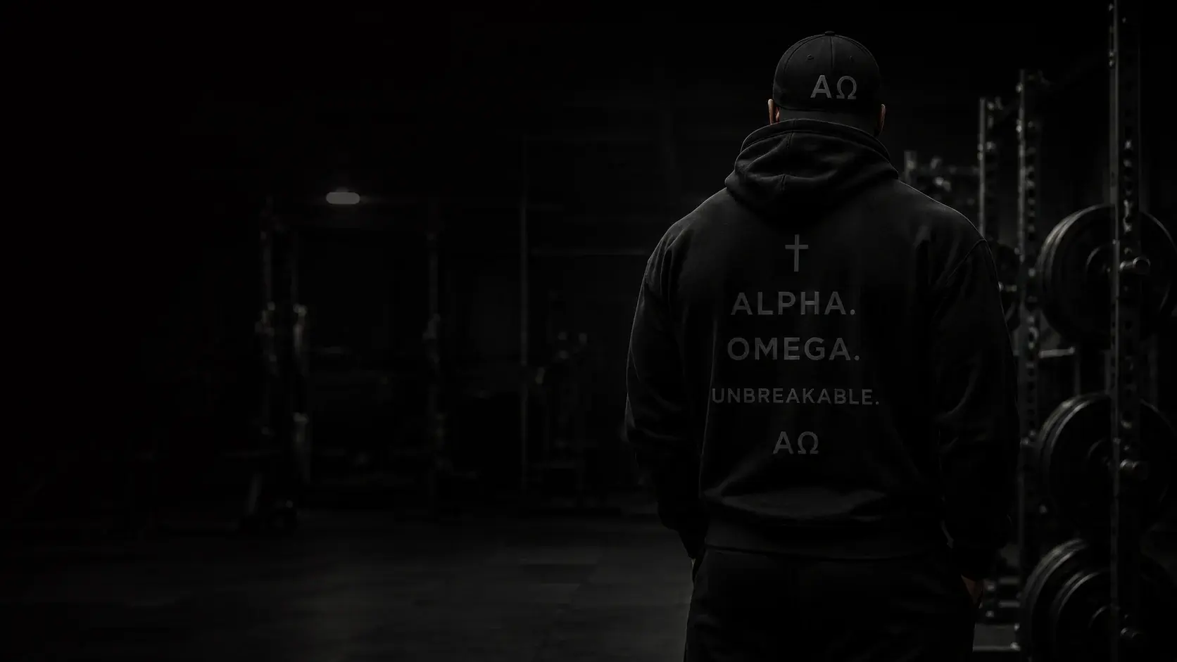 Athlete from behind wearing the Alpha Omega Unbreakable hoodie in a dark gym